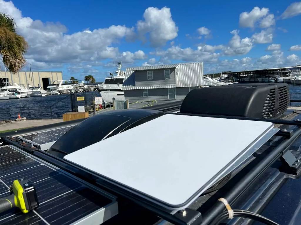 A compact Starlink Mini dish mounted on an RV roof with clear northern sky view during sunset setup.
